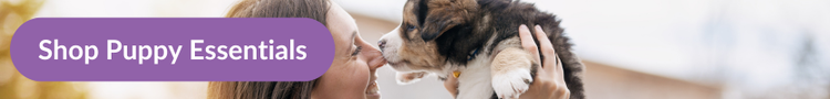 A female owner holding up her new puppy to kiss its nose with overlay text that reads &#34;Shop Puppy Supplies&#34;